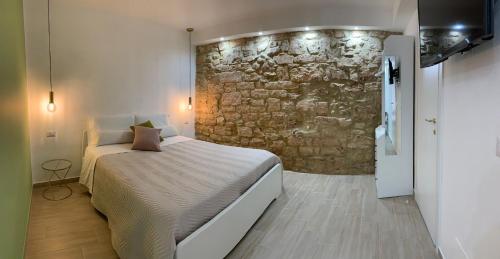 1 dormitorio con cama y pared de piedra en La Pelliccia en Bari