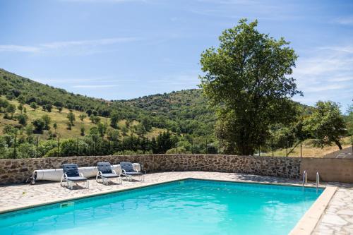 a swimming pool with two chairs and a rock wall at Gîtes du Pont de Calmel in Rieussec