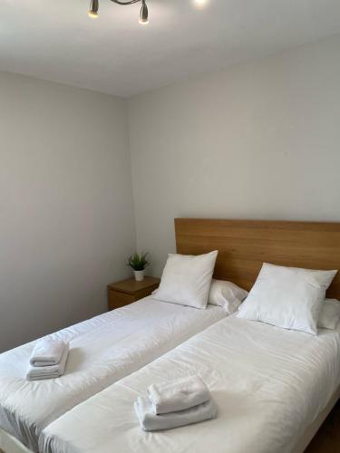 two beds in a room with white sheets and towels at Mundaka best views house in Mundaka