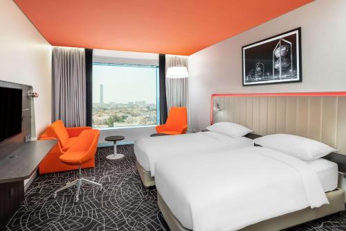 a hotel room with a large bed and orange chairs at Park Inn by Radisson Jeddah Madinah Road in Jeddah
