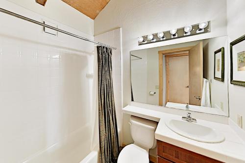 Un baño con lavabo, inodoro y espejo. en Alpine Retreat, en Truckee