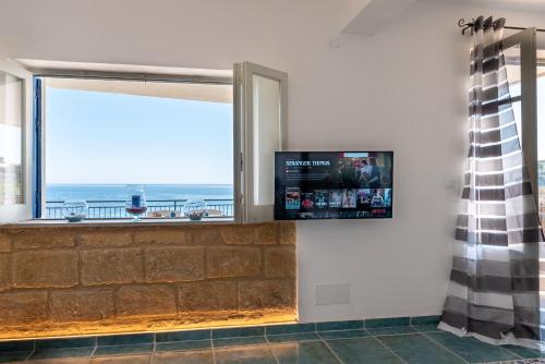 a room with a large window and a flat screen tv at Dimore di mare - Beachfront Apartments in Santa Flavia