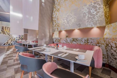 a dining room with tables and pink chairs at Radisson Blu Gautrain Hotel, Sandton Johannesburg in Johannesburg