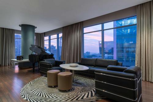 a living room with a couch and a piano at Radisson Blu Gautrain Hotel, Sandton Johannesburg in Johannesburg