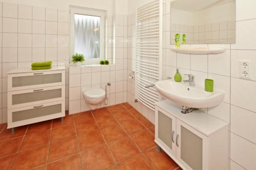 a white bathroom with a sink and a toilet at Usedom Ferienwohnungen Riwa ruhig in Kölpinsee