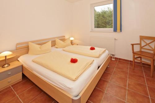 a bedroom with a bed with two red flowers on it at Usedom Ferienwohnungen Riwa ruhig in Kolpinsee