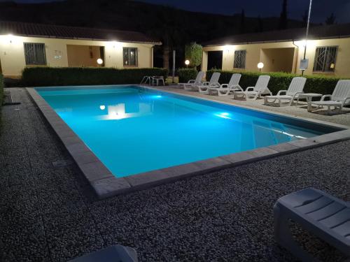 a swimming pool at night with chairs around it at Makara Case Vacanza in Eraclea Minoa