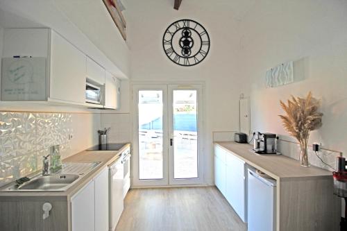 eine Küche mit weißen Schränken und einer Uhr an der Wand in der Unterkunft Villa Mer Nature in Frontignan