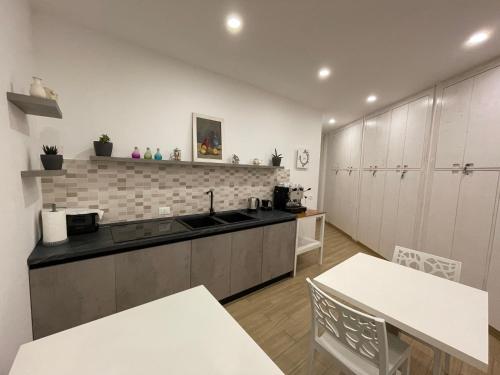 a kitchen with white cabinets and a sink and tables at IL GIARDINO NASCOSTO in Portopalo