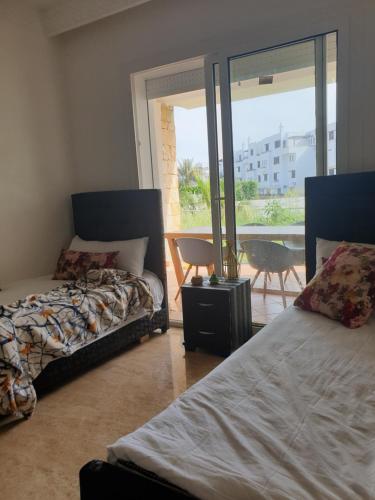 a bedroom with two beds and a balcony at Playa del Pasha in Restinga Smir