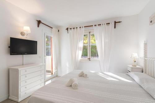 a white bedroom with a bed and a tv at Gorgeous renovated Cala Sant Vicenc Beach Villa in Cala de Sant Vicenc