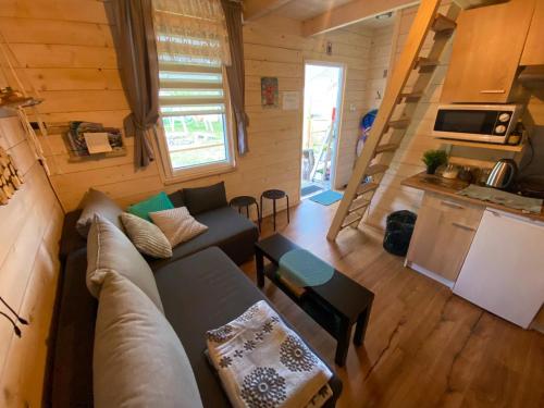 ein Wohnzimmer mit Sofa und eine Küche in einem winzigen Haus in der Unterkunft Brzozowy Gaj in Bachowice