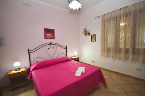 a bedroom with a pink bed and two night stands at Cascina degli Ulivi in Castelluzzo