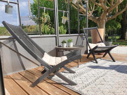 a patio with two chairs and a table and a tree at Mas des muses in LʼIsle-sur-la-Sorgue