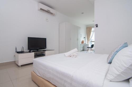 ein weißes Schlafzimmer mit einem großen Bett und einem TV in der Unterkunft Shaftsbury Cyberjaya by IdealHub in Cyberjaya