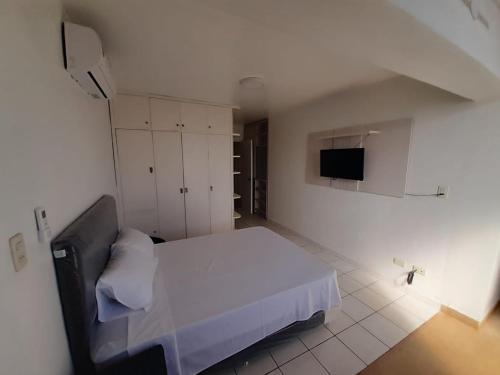 1 Schlafzimmer mit einem weißen Bett und einem TV in der Unterkunft Departamento en el centro de la ciudad in Encarnación