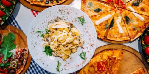 a table topped with plates of pizza and pasta at Crowne Plaza Bahrain by IHG in Manama