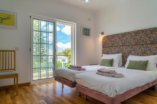 een slaapkamer met 2 bedden en een groot raam bij LV Premier Algarve FU1- pool, AC, garden, sea view in Moncarapacho
