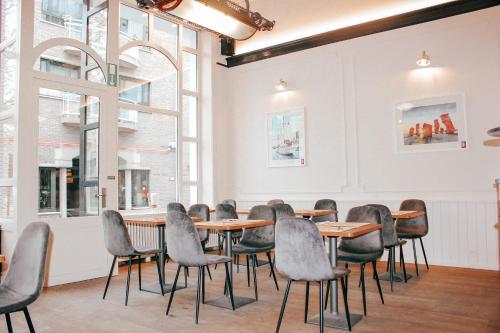 Cette chambre comprend des tables, des chaises et des fenêtres. dans l'établissement Alpha Hotel, à Ostende