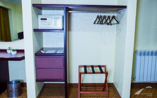 a refrigerator with a microwave and a chair in a kitchen at Hotel Concorde in Toluca