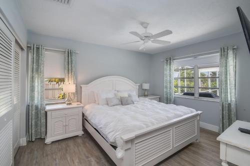 a white bedroom with a large white bed and windows at Mermaid Manor; Waterfront with Direct Ocean Access and Private Heated Pool in Marco Island
