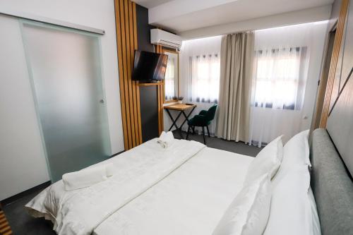 a bedroom with a large white bed and a desk at Glavatarski Han in Glavatartsi
