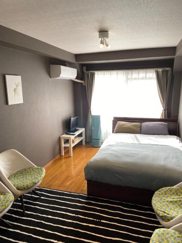 1 Schlafzimmer mit einem Bett, 2 Stühlen und einem Fenster in der Unterkunft Dazaifu - Hotel - Vacation STAY 58481v in Dazaifu