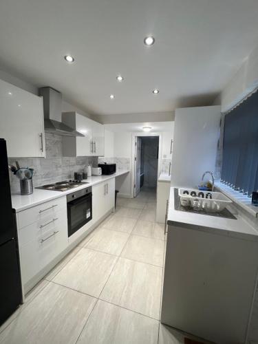 a large kitchen with white cabinets and appliances at 4 BR, Large & Modern Private House Central Location in Newcastle upon Tyne
