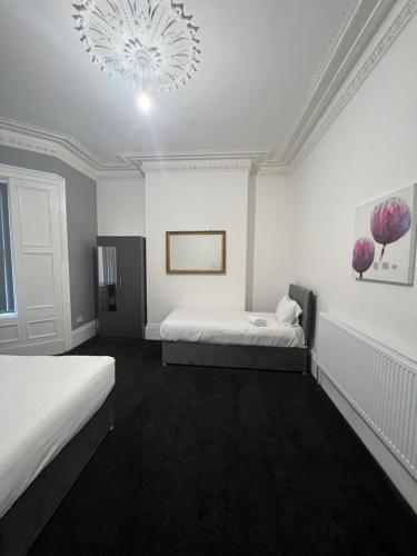 a white room with two beds and a chandelier at 4 BR, Large & Modern Private House Central Location in Newcastle upon Tyne
