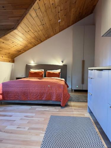 a bedroom with a bed and a wooden ceiling at Apartamentai Gėlių Vila in Nida