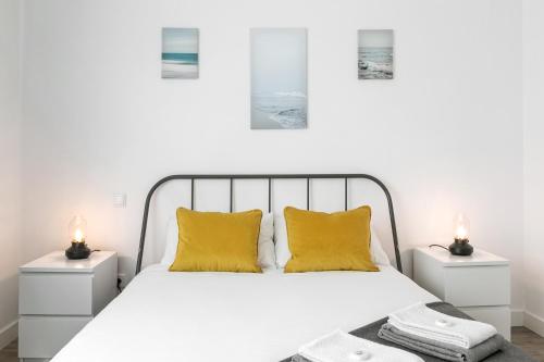 1 dormitorio con cama blanca y almohadas amarillas en SURFERS PARADISE en Peniche