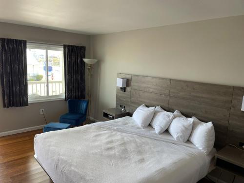 Un dormitorio con una cama blanca y una silla azul. en Kings Arms Motel, en Ocean City
