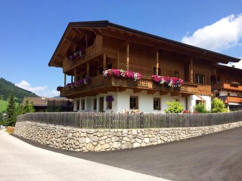 een houten huis met bloemen op een stenen muur bij Alpbach Loft in Alpbach