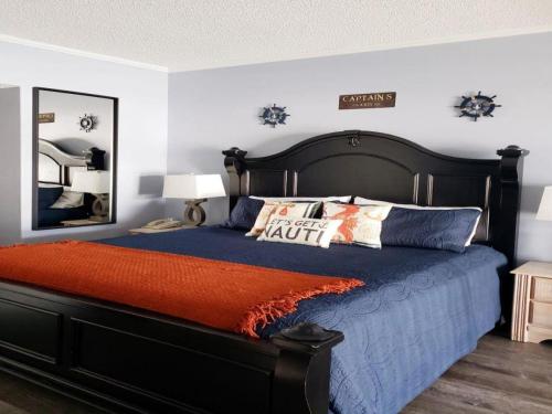 een slaapkamer met een zwart bed met kussens en een spiegel bij Inn at Camachee Harbor View 12 in St. Augustine