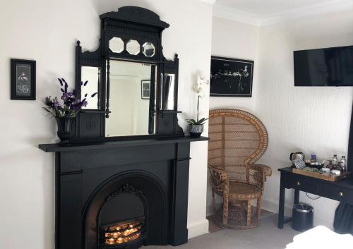 a black fireplace with a mirror on top of it at High Tor Guest House in Whitby