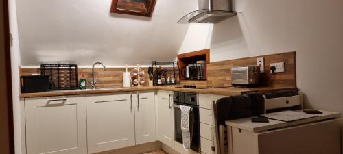 a kitchen with white cabinets and a sink and a microwave at Kirkwall town centre apartment in Kirkwall