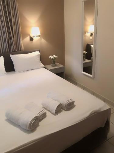 a bedroom with a bed with towels and a mirror at Fenareti Apartments in Skala Eresou