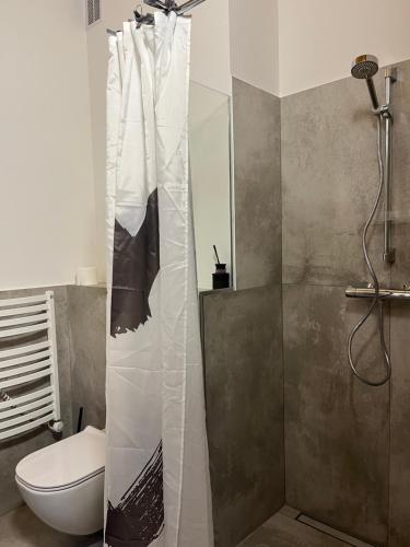 a bathroom with a shower with a toilet and a shower curtain at Apartamentai Gėlių Vila in Nida