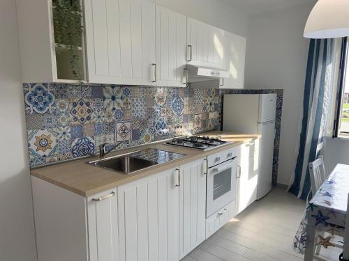 a kitchen with white cabinets and a sink and a refrigerator at Edoardo e Franca in Minturno