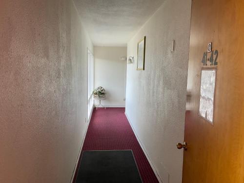 an empty hallway with a door and a red carpet at Front Street Inn in Crescent City