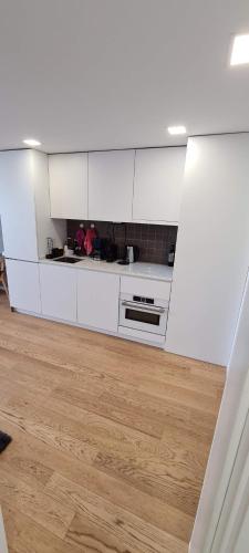 a kitchen with white cabinets and a wooden floor at Uno Al Mar - Estúdio Praia in Vila Nova de Gaia