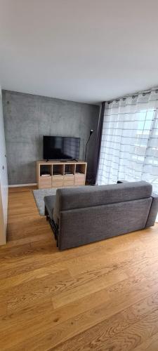 a living room with a large couch and a television at Uno Al Mar - Estúdio Praia in Vila Nova de Gaia