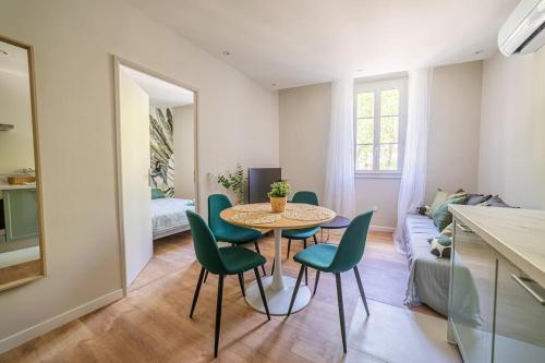 a dining room with a table and green chairs at Le Pearl Appartement de charme en bord rivière in Collobrières
