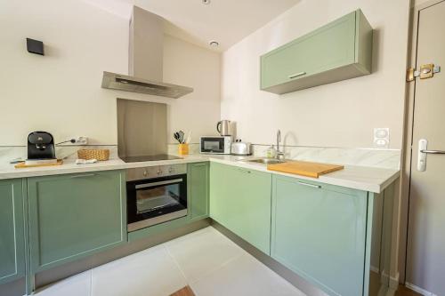 a kitchen with green cabinets and white counter tops at Le Pearl Appartement de charme en bord rivière in Collobrières