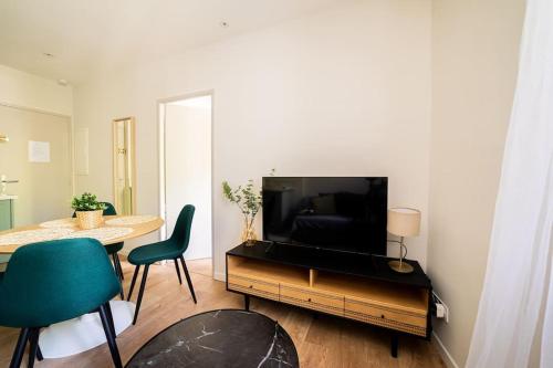 a living room with a television and a table and chairs at Le Pearl Appartement de charme en bord rivière in Collobrières
