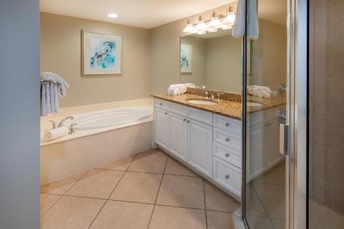 a bathroom with a tub and a sink and a shower at Escapes! To The Shores Orange Beach, A Ramada by Wyndham in Orange Beach