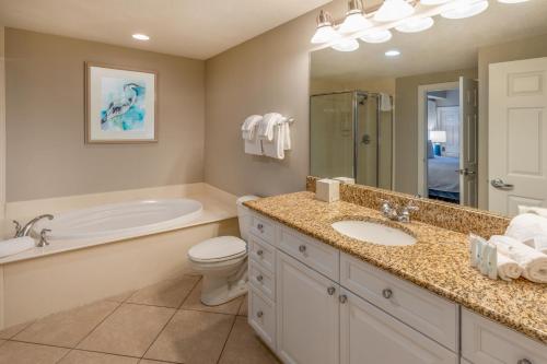a bathroom with a tub and a toilet and a sink at Escapes! To The Shores Orange Beach, A Ramada by Wyndham in Orange Beach