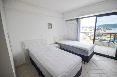 2 camas en una habitación con ventana grande en 1060 - Cobertura Duplex com Linda Vista Para o Mar, en Bombinhas