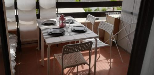 une table blanche et des chaises dans une pièce avec une fenêtre dans l'établissement Appartement terrasse vue mer, plage gorguette à 1 minute à pied, wifi,clim parking collectif, à Sanary-sur-Mer