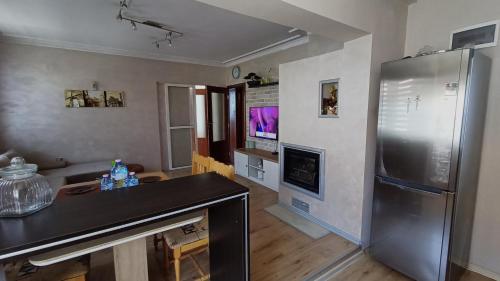 uma cozinha com um frigorífico de aço inoxidável e uma sala de estar em Nikolovi Home Apartments em Pomorie